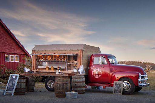 This image shows a rustic taps bar truck set up for an event at a venue