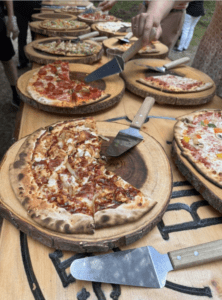 Beautiful woodfired pizzas laid out on wooden cutting boards for family style catering using farm-to-table ingredients